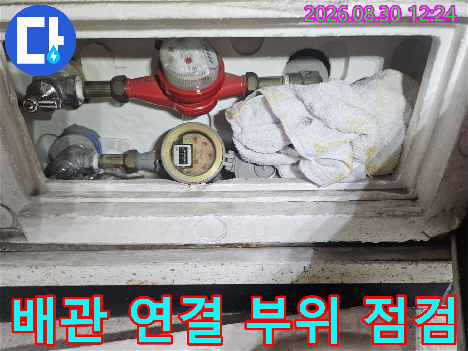 수도 계량기와 밸브 부근의 배관 연결 상태를 세밀하게 관찰하고 있습니다.