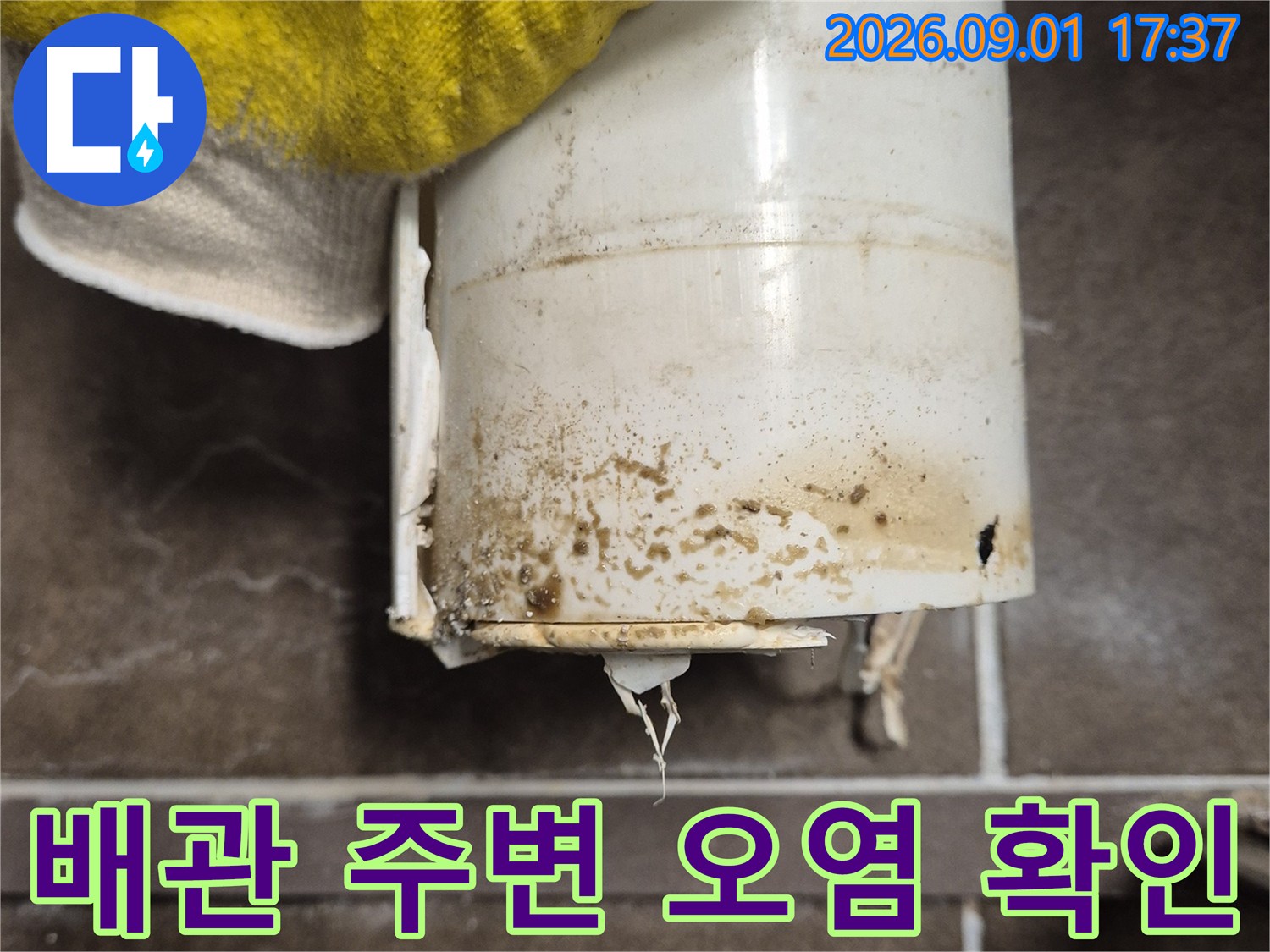 하얀색 오수관에 묻은 갈색 물때와 오염물을 근접 촬영한 사진입니다.