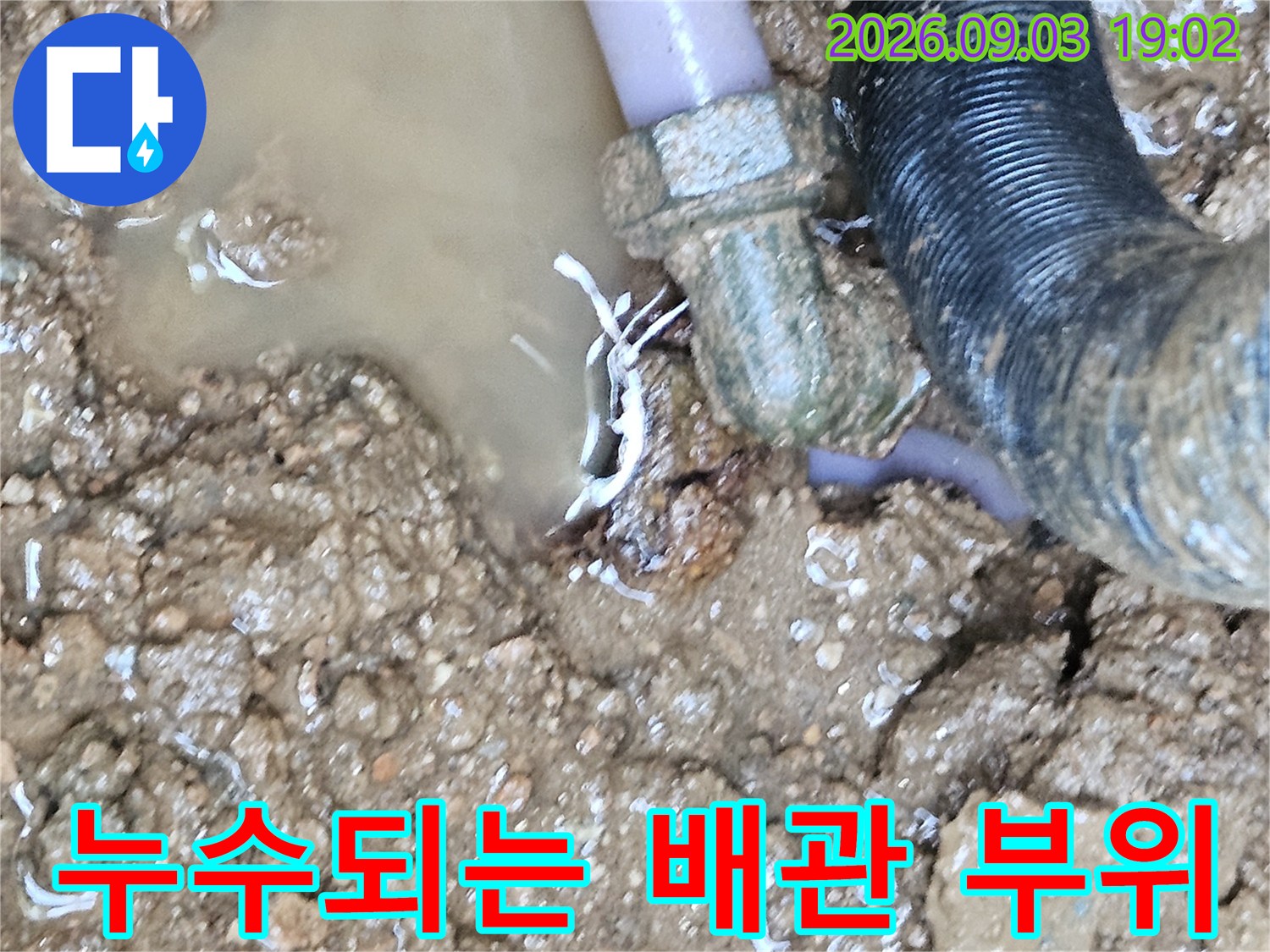 흙 속에 파묻힌 수도 배관-연결부에서 물이 새어 나오는 사진