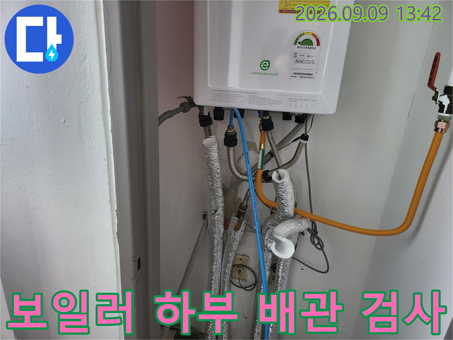 보일러실의 여러 배관들 사이로-파란색 호스와 압력 측정 장비가-연결되어 있는 모습입니다.