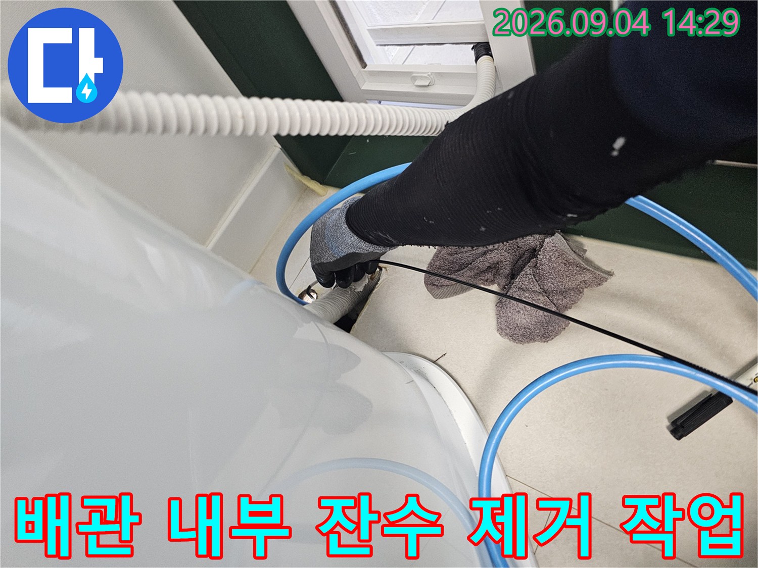 에어컨 매립 배관 내부에 고인 물을 제거하기 위해 흡입 장비를 사용하는 모습입니다.