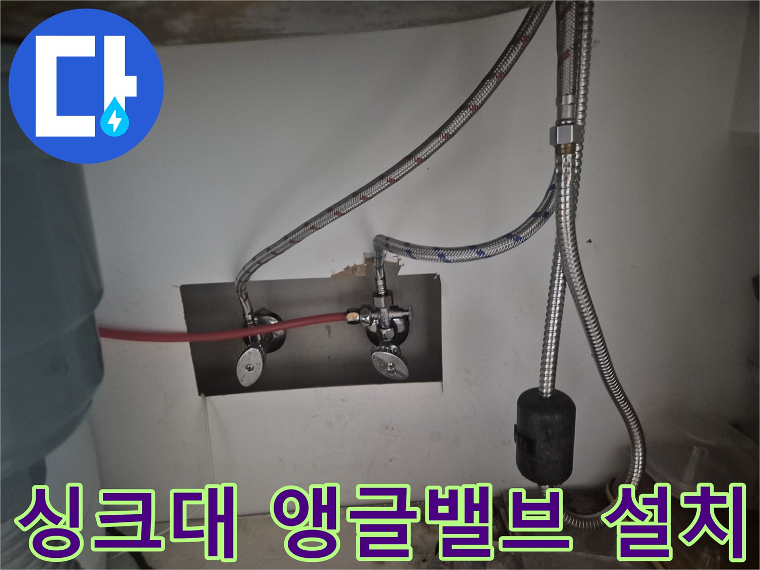 싱크대 밑 벽면 배관과 은색 호스 연결부 상세 사진