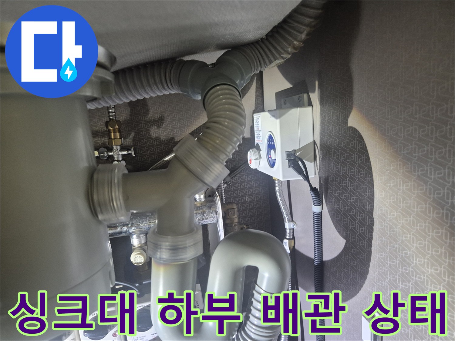 싱크대-하부의-회색-배수-호스와-벽면-콘센트 연결 부위