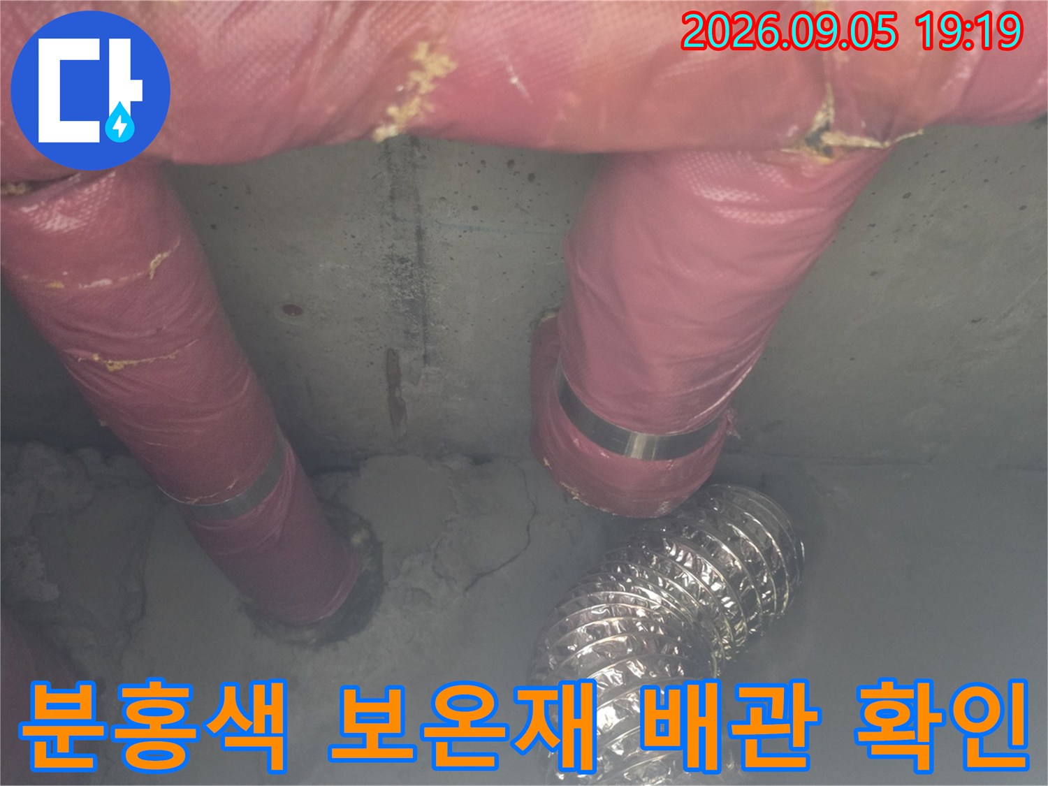 천장 내부의 분홍색 보상재와 은색 자재가 포함된 배관 구조물 사진