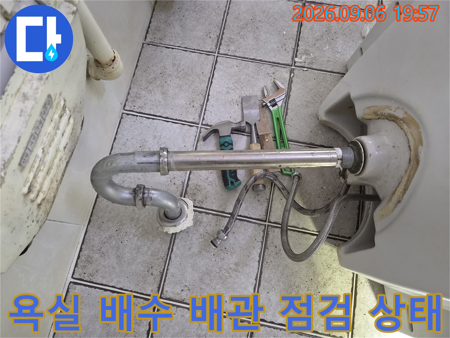은색 배관 주위의 작업용 몽키스패너와 공구들
