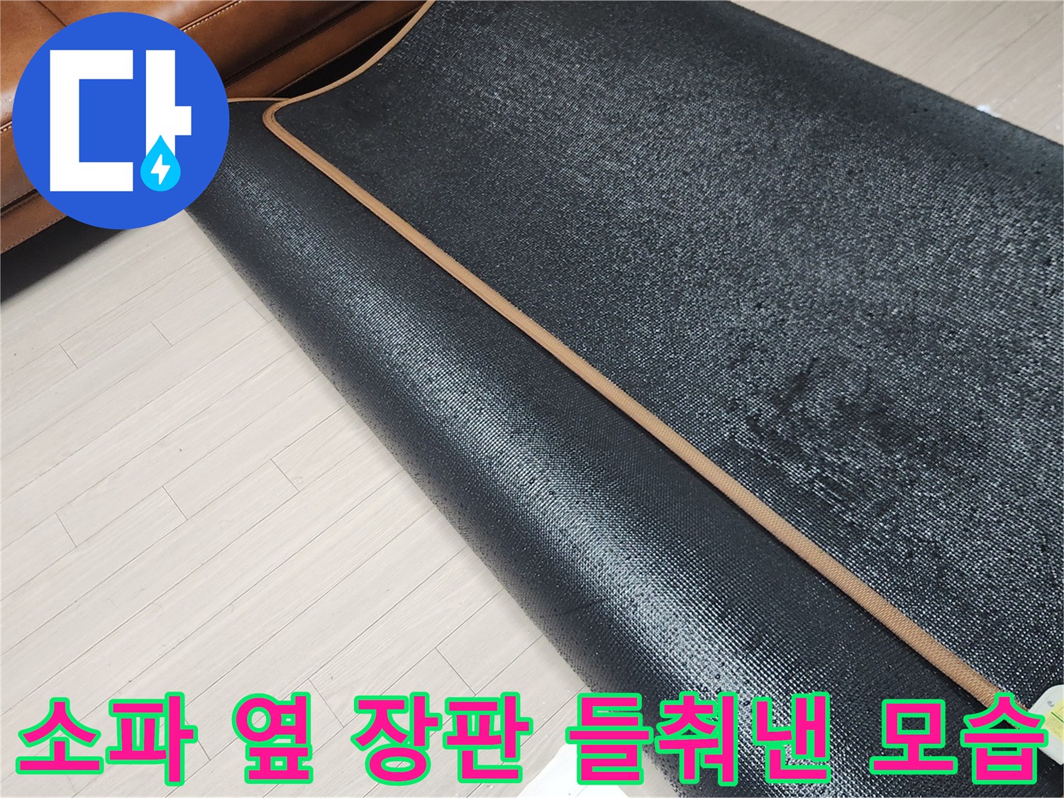 거실 소파 옆 바닥의 습기를 확인하기 위해 장판을 걷어낸 사진입니다.
