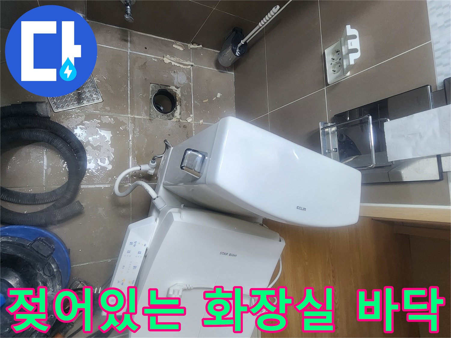 변기를 들어낸 후 드러난 젖은 타일과 배수구 주변 환경