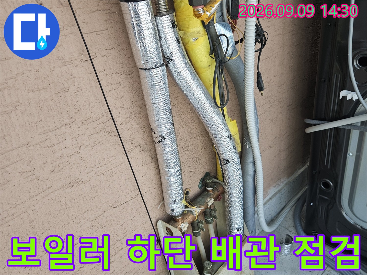 보일러 하단의 은박 단열재로 감싸진 배관 연결 부위 상세 촬영 사진