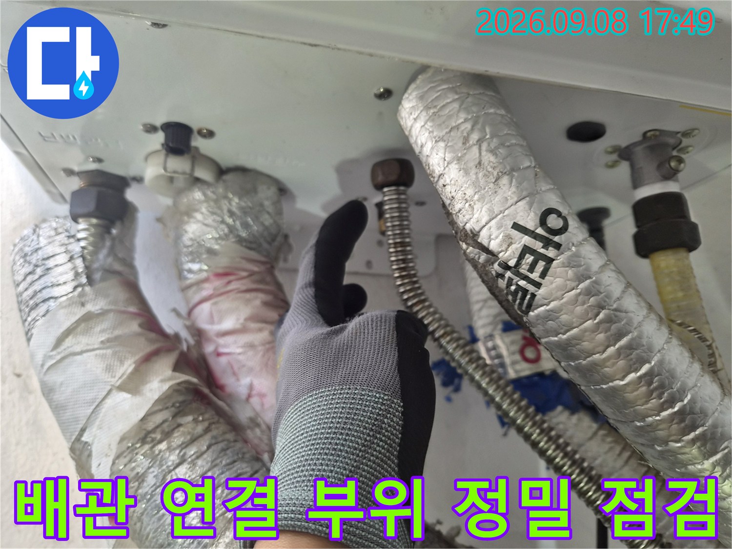 작업자가 장갑을 끼고 보일러 배관의 금속 연결부를 가리키는 사진