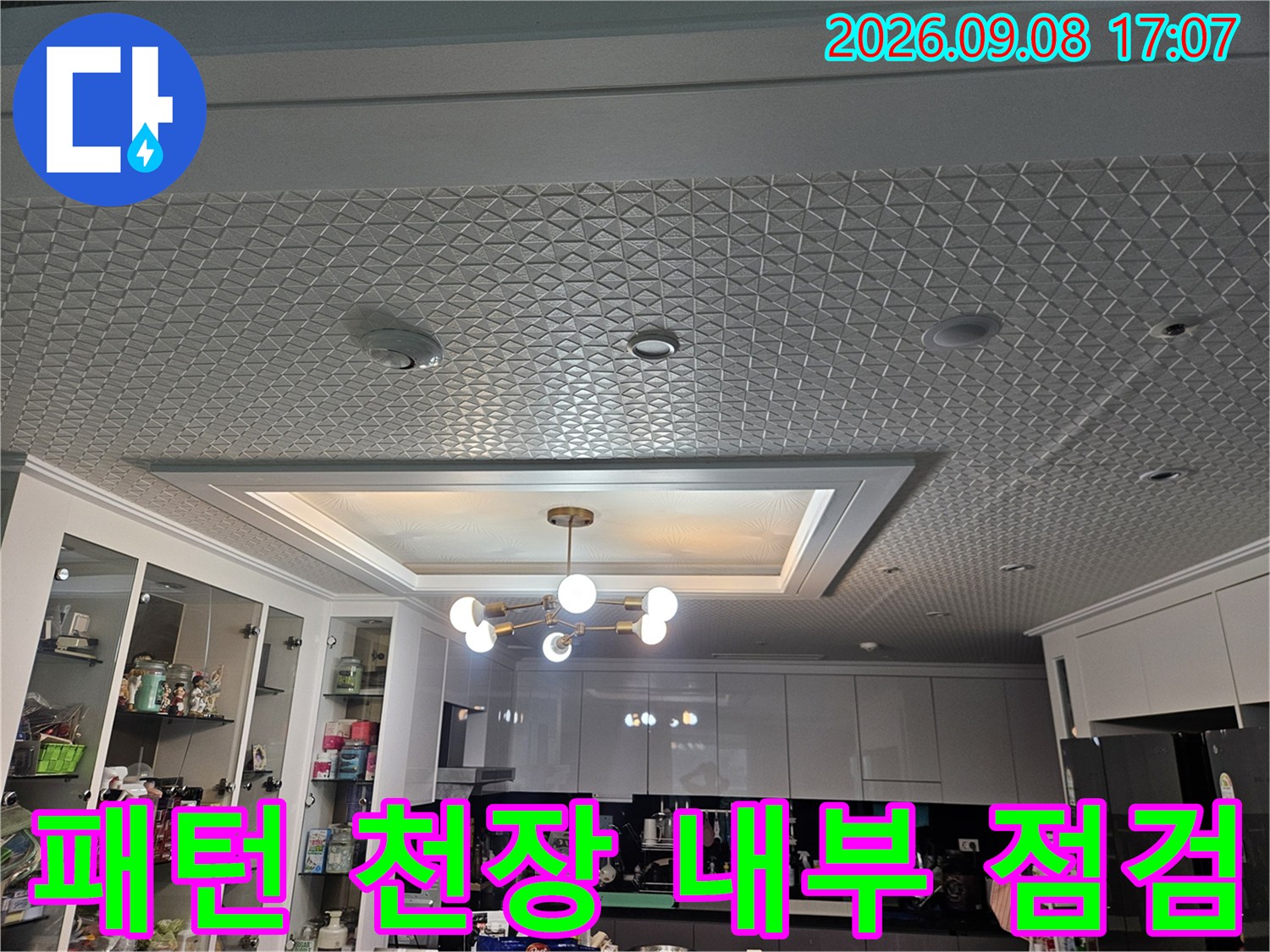 기하학적 패턴의 천장 마감재와 매립형 조명이 설치된 실내 모습입니다.