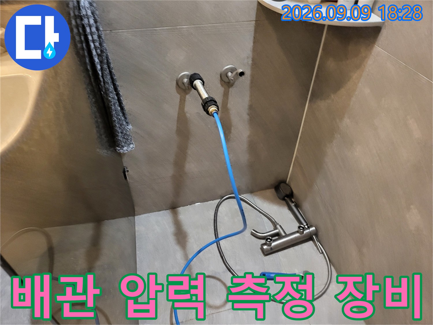 벽면 배관에 연결된 파란색 호스와 공압 테스트 장치 모습입니다.