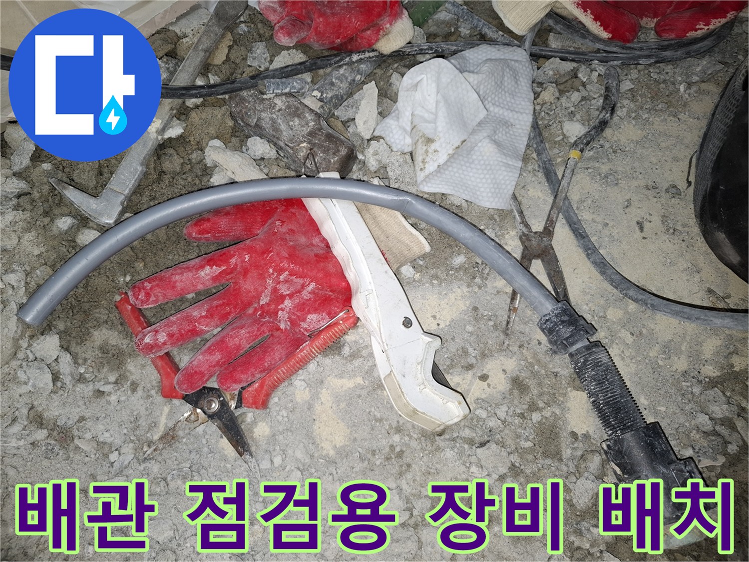 공사 현장 바닥에 놓인 배관 호스와 붉은색 작업 장갑 세트
