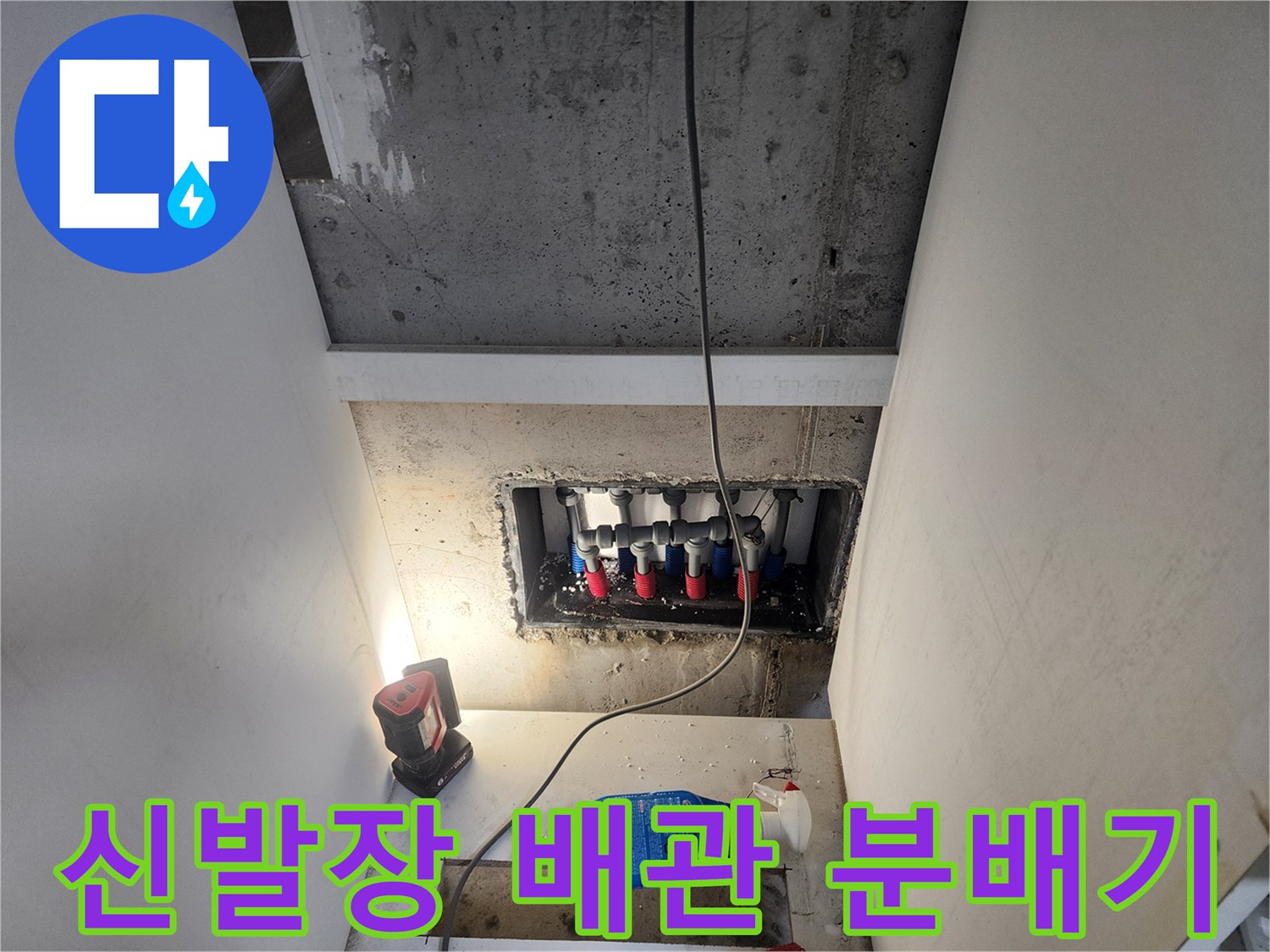 신발장 하단에 노출된 빨간색과 파란색 배관 분배기 모습