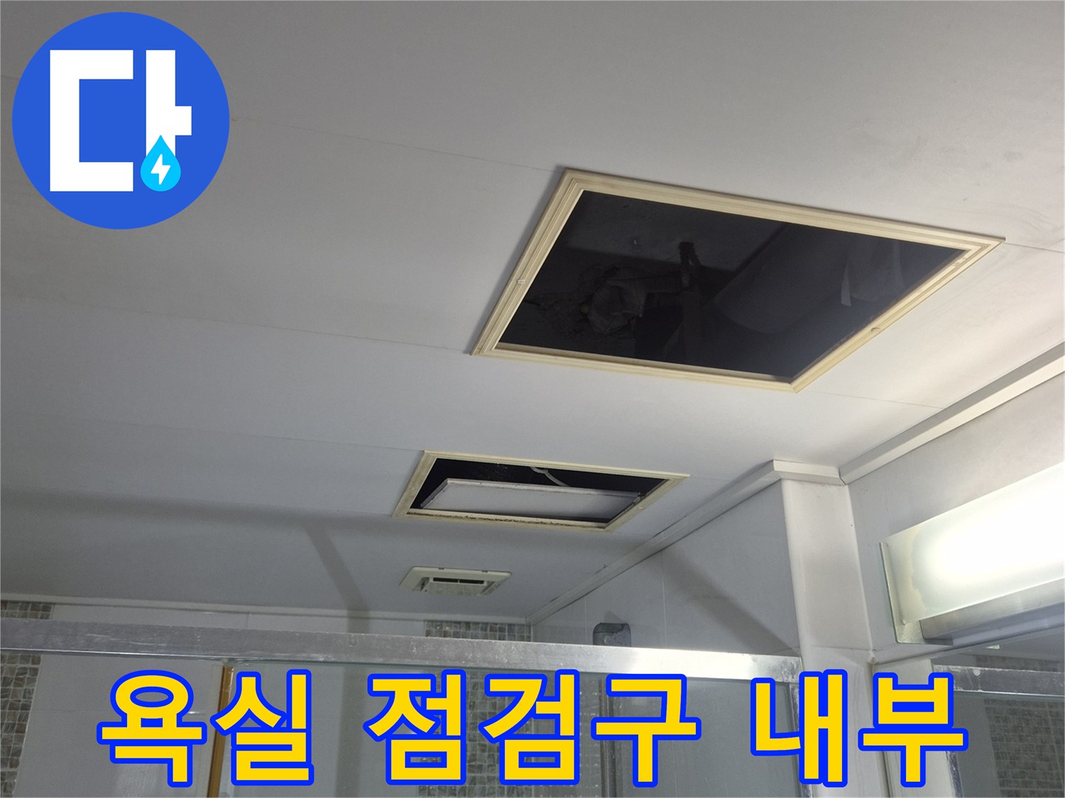 화장실 천장의 점검구를 열어 배관 상태를 확인하는 장면입니다.