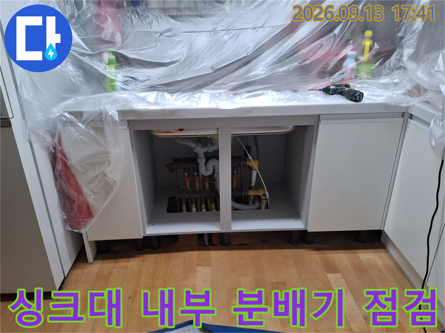보양재로 덮인 싱크대 하부장의 보일러 분배기 배관 모습