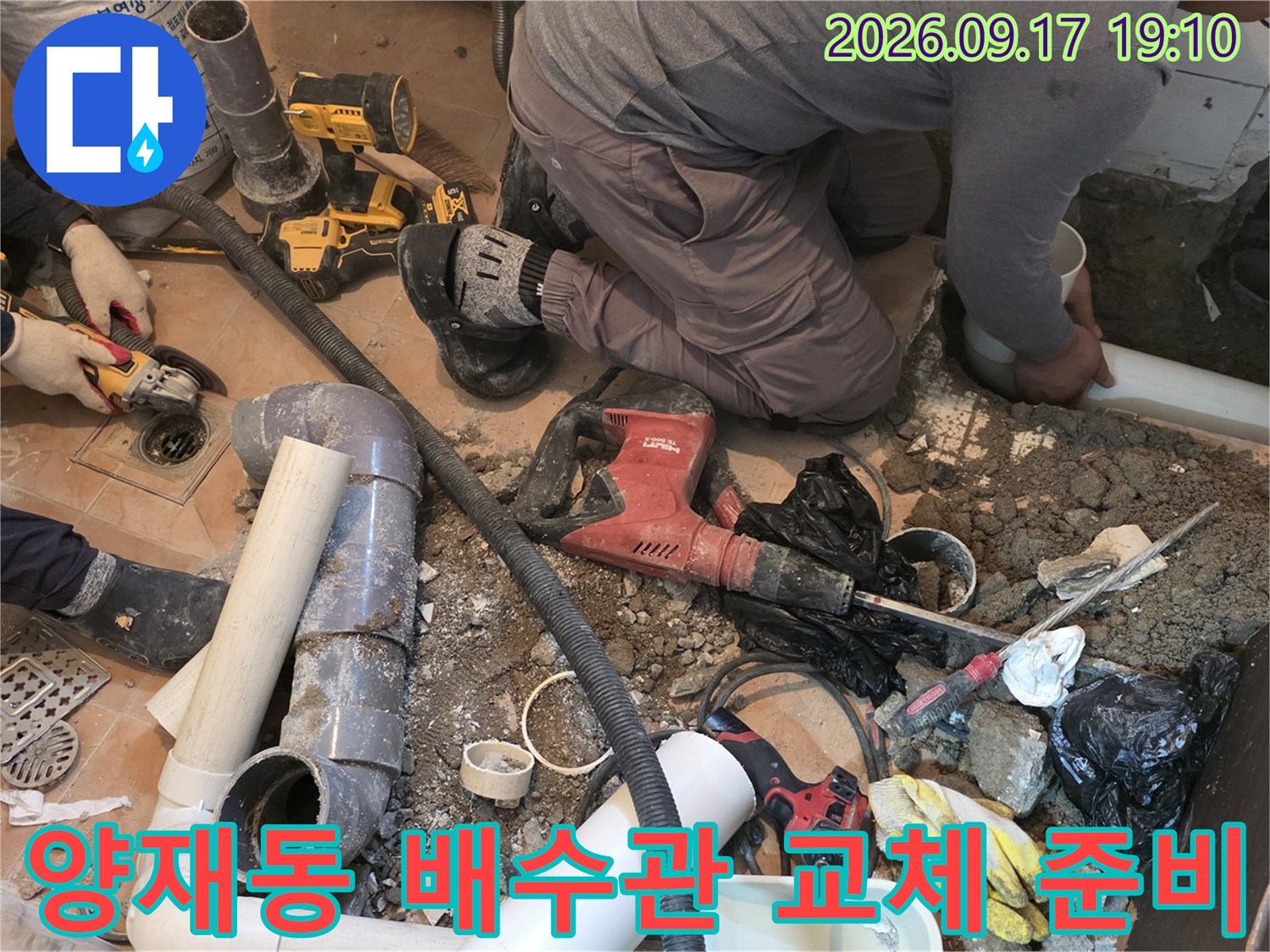 굴착된 화장실 바닥에 놓인 PVC 배관과 작업용 드릴 장비입니다.