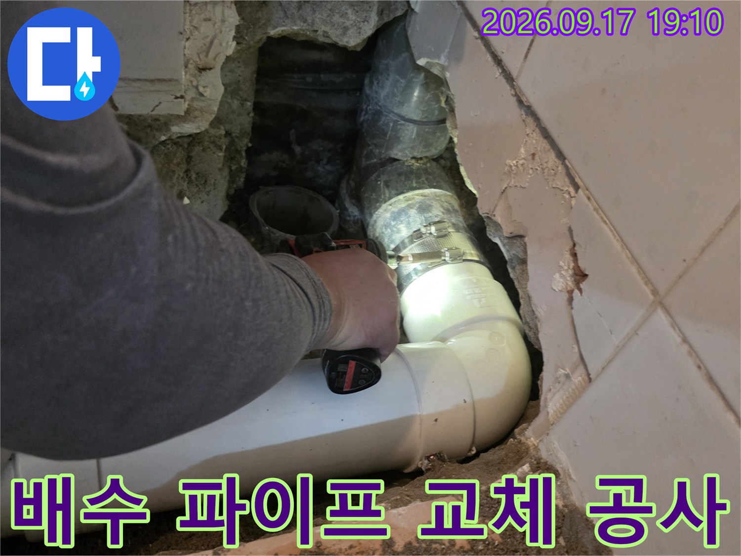 타일 틈새 사이로 보이는 새로 설치된 하얀색 PVC 배관입니다.