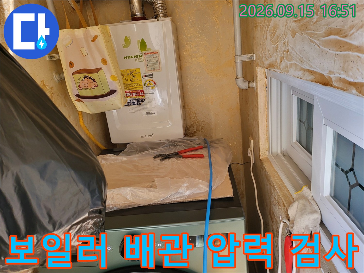 보일러 하단 배관에 설치된 노란색 호스와 점검 도구입니다.