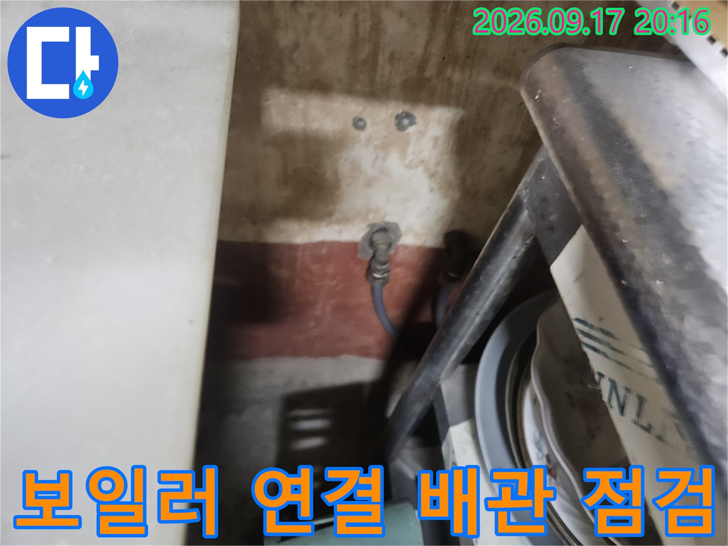 보일러 하부의 파란색 배관과 연결 소켓 부위의 근접 촬영 사진입니다.