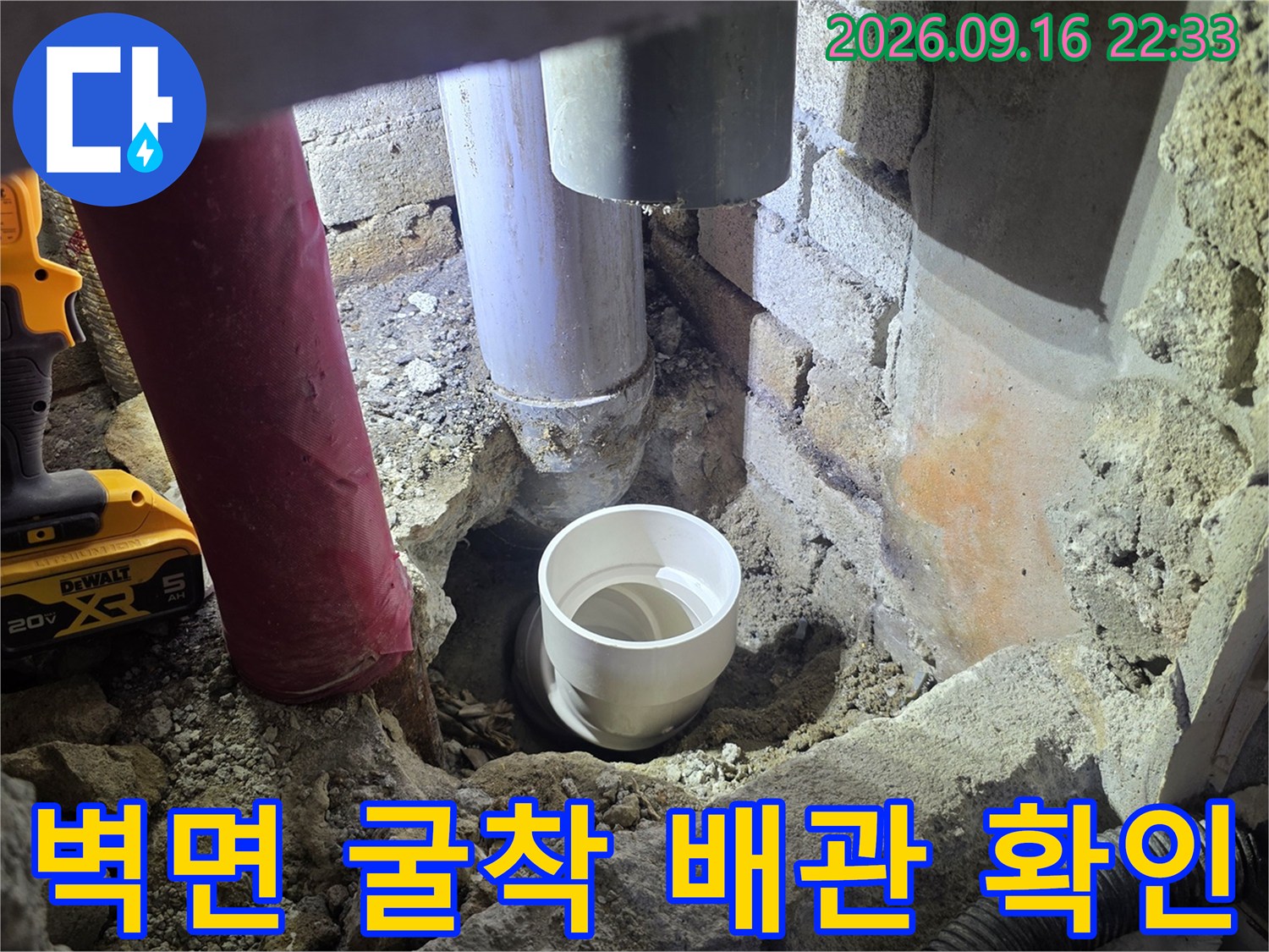 굴착된 벽면 사이로 보이는 흰색 배관과 작업 도구