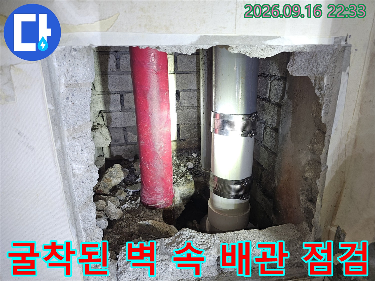 벽면을 깨서 드러낸 빨간색과 은색의 배관 연결 부위입니다.