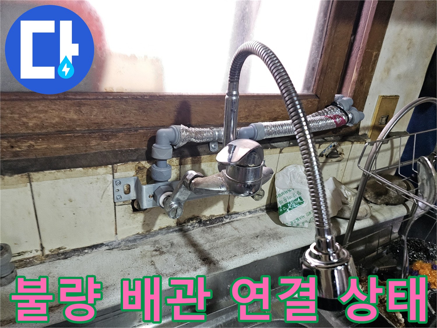 주방 싱크대 주변의 노후된 수도 호스와 불규칙한 배관 배열